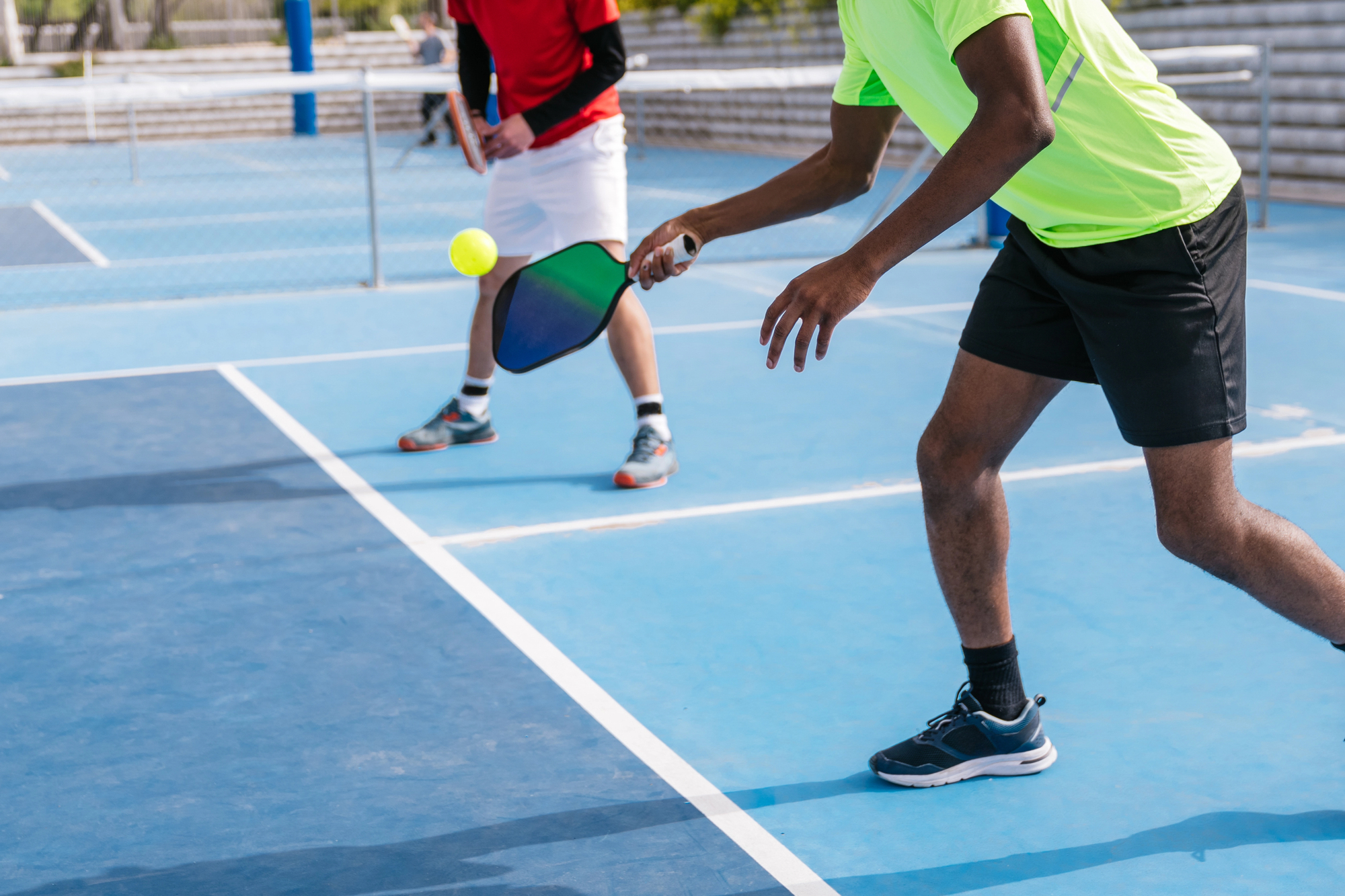 Close-up of a multiracial group of pickleball players focused on hitting the ball during a game on a blue outdoor court. Concept of focus and teamwork.