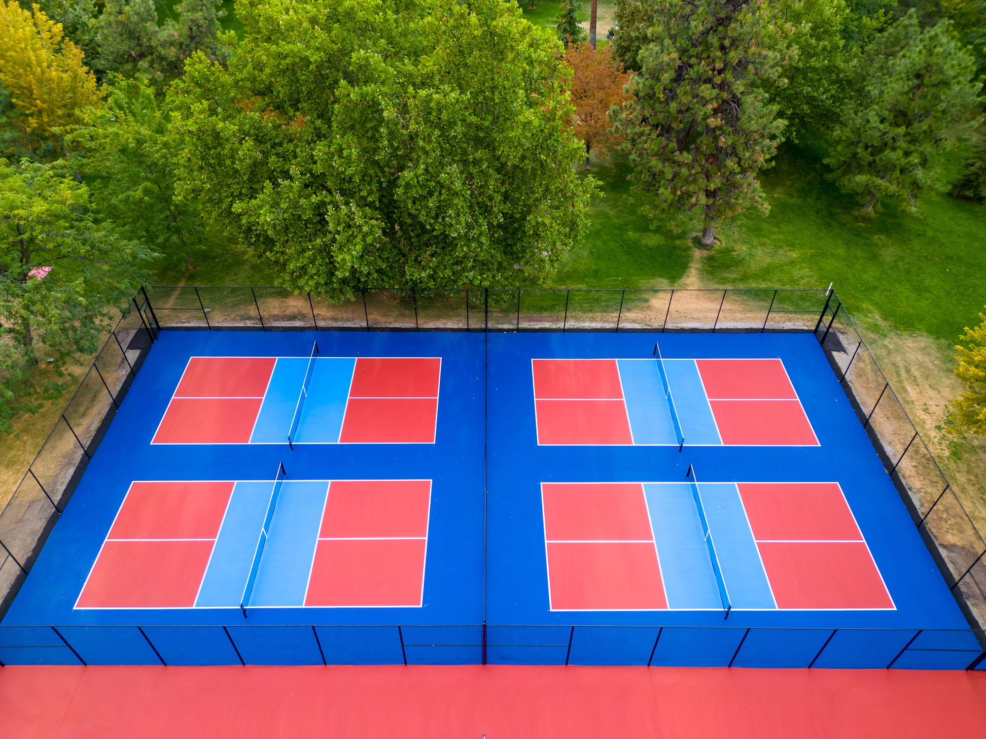 Drone aerial view from above showcases colorful pickleball and tennis courts sports surface from above.