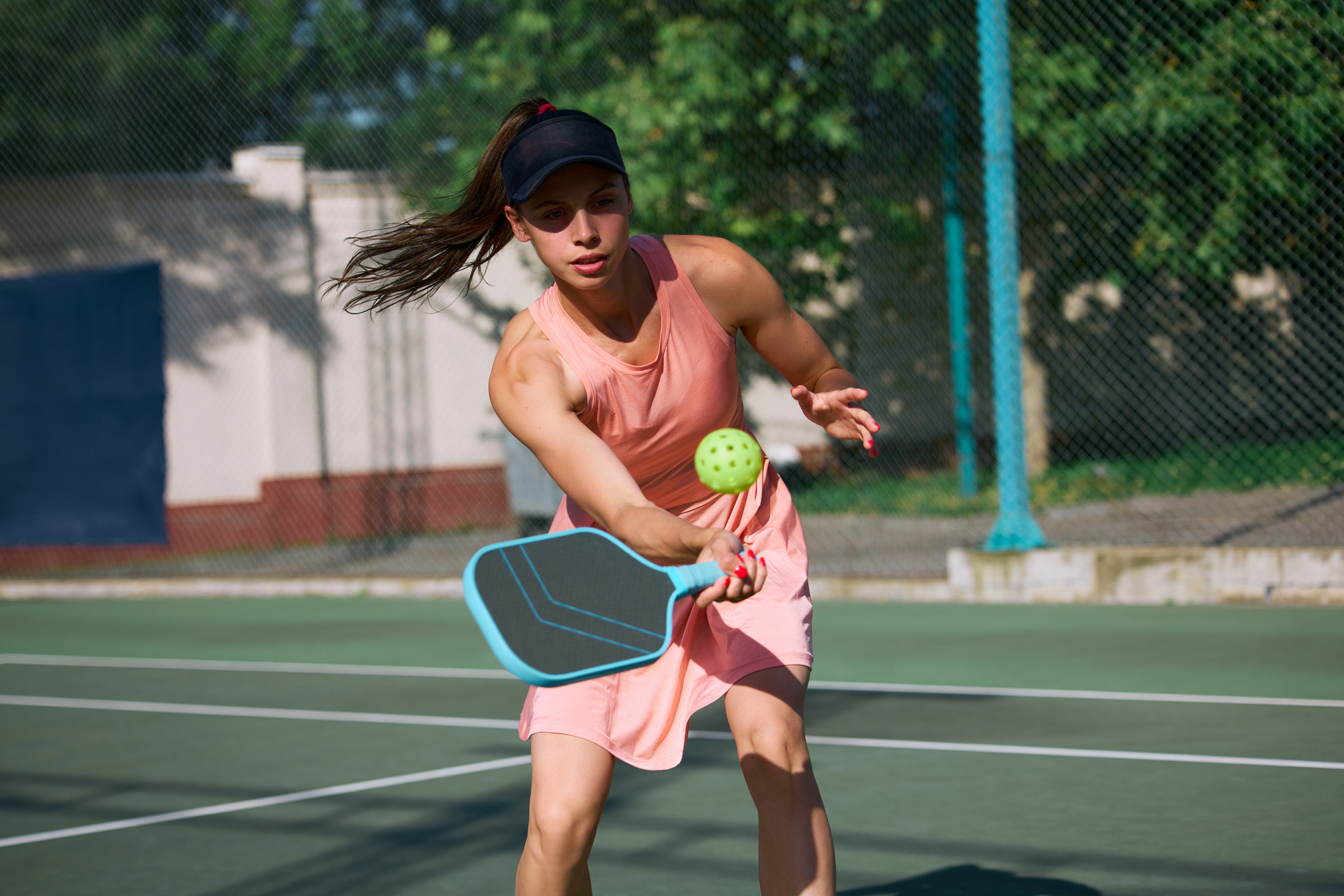 Woman executing controlled forehand return in pickleball match.