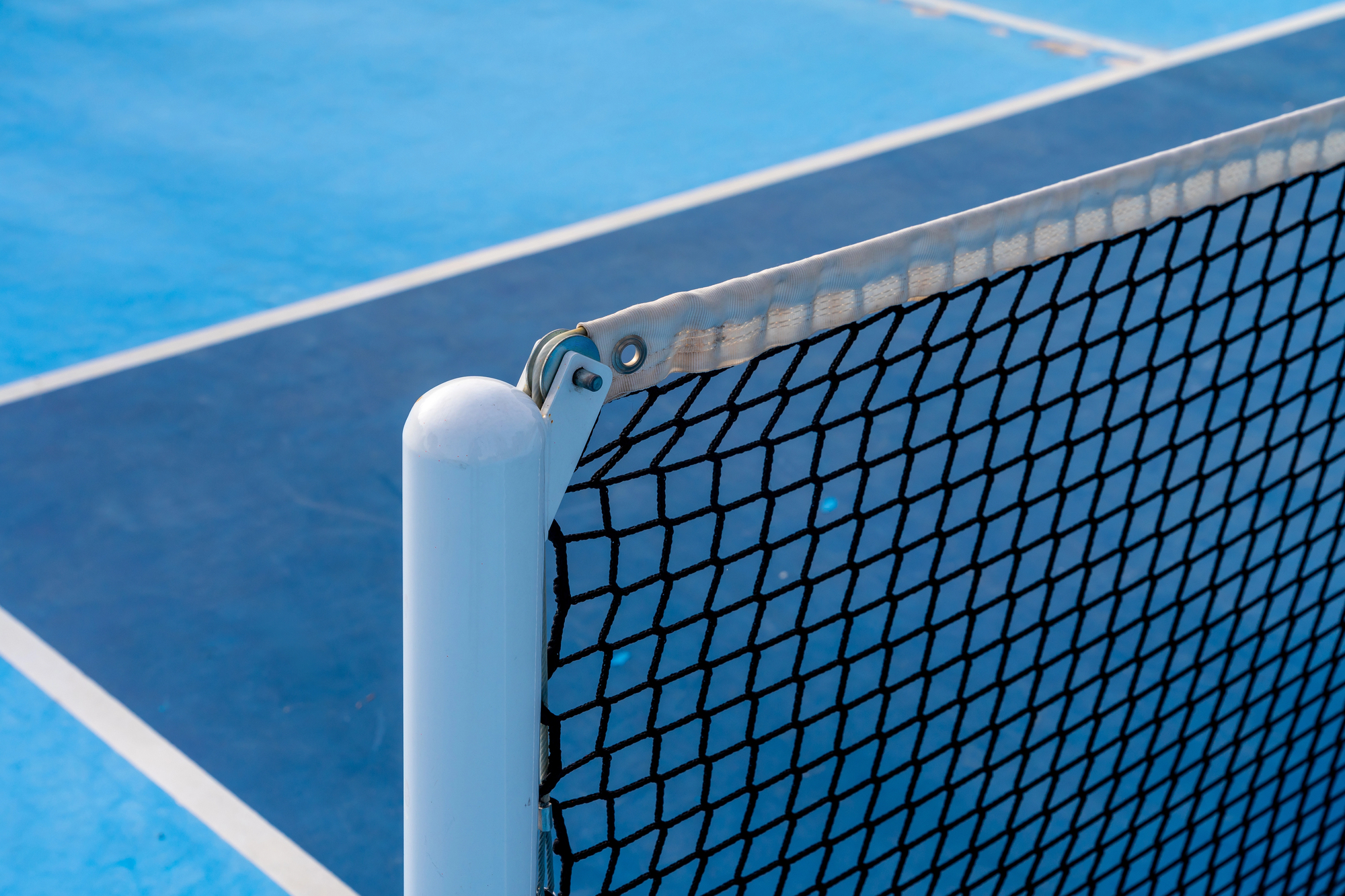Close-up of a pickleball net post on a blue court